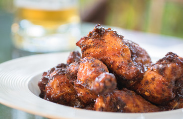 mexican style spicy grilled chicken in white plate, blurred mug of beer in background
