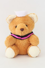 Teddy bear wearing a nurse hat on a white background.