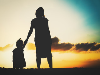 Silhouette of mother and daughter walking at sunset
