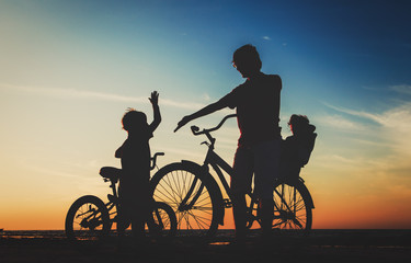 Obraz premium father with two kids on bikes at sunset beach