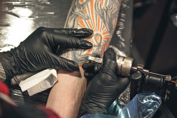Fototapeta na wymiar Master drawing tattoo on arm of man