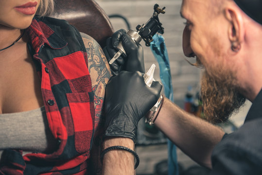 Happy man creating tattoo on hand in room