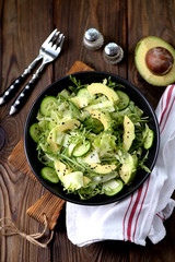 Organic healthy salad of iceberg, avocado and cucumber with olive oil and sesame seeds.