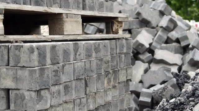 Tilt up shot of recycled paving stones or bricks stacked on pallets and in a pile ready for re-use in another construction project.