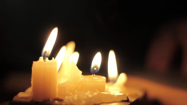 Monk reading and touching a yellow pages of old book. Close-up candle light.