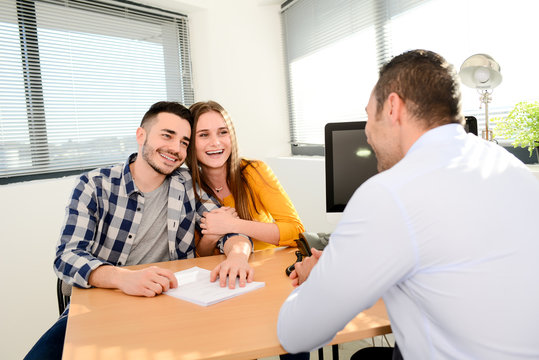 happy young couple in office with businessman on business buying agreement contract signature