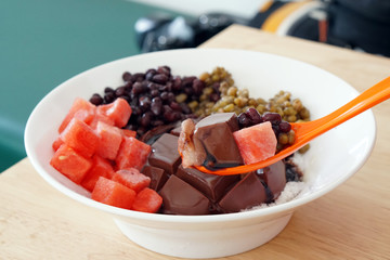 Bowl of Cold Tofu Pudding with Watermelon, Red Bean and Mung Bean on top with chocolate sauce on shaved ice - Traditional Taiwanese Dessert.