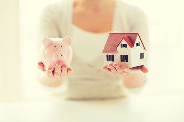 close up of woman with house model and piggy bank