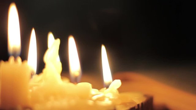 Monk reading and touching a yellow pages of old book. Light of candle in dark room