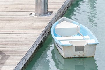Fototapeta na wymiar White and blue rowboat anchored at the sea dock.