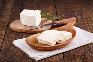 Sliced fresh brined white cheese from cow milk on wooden table