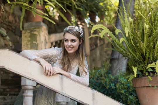 Beautiful young bride leaning on railing in white wedding dress