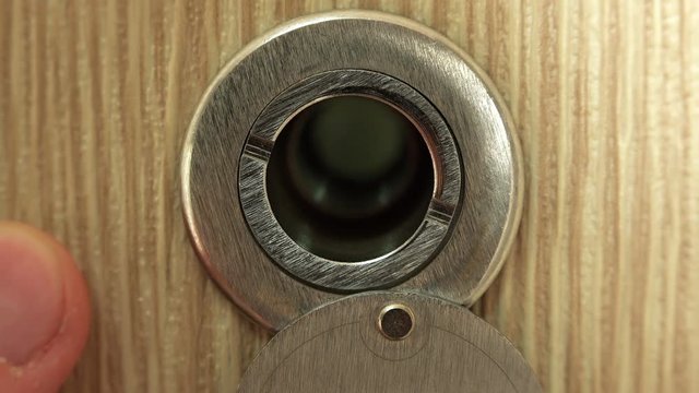 Close-up View of Man Looking Through the Door Peephole. 4K