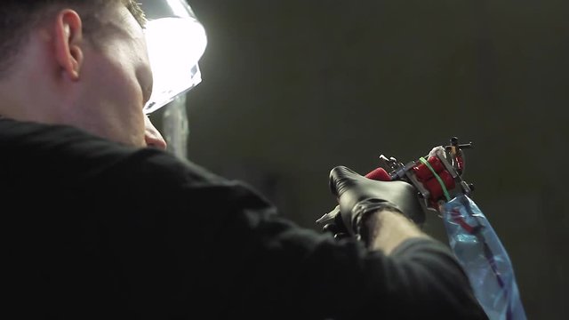 The tattoo artist makes a black tattoo on man shoulder