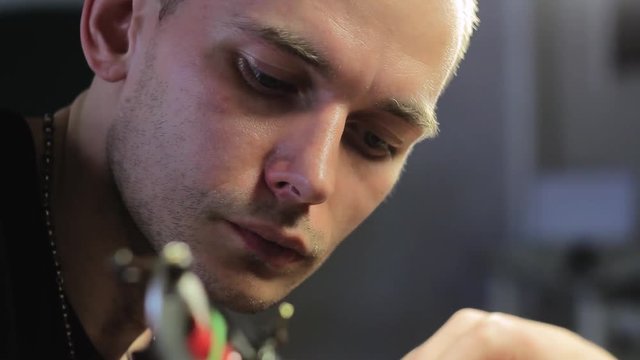 The tattoo artist makes a black tattoo on man shoulder