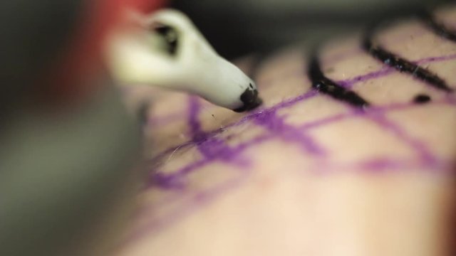 Male tattoo artist makes a tattoo on shoulder in black ink, Close-up shooting