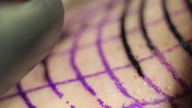Male tattoo artist makes a tattoo on shoulder in black ink, Close-up shooting