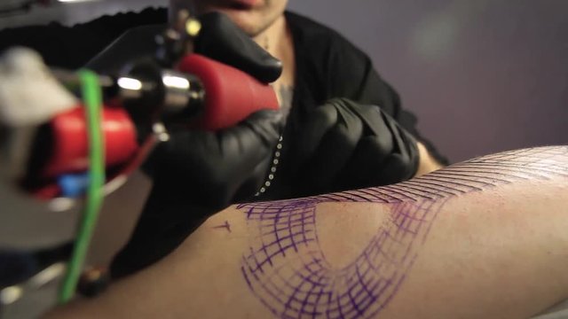 The tattoo artist makes a black tattoo on man shoulder