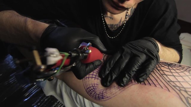 The tattoo artist makes a black tattoo on man shoulder