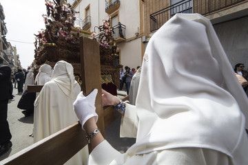 Penitent dressed in purple tunic of velvet resting on wooden cross during atonement station on Holy Week, Andalusia, Spain
