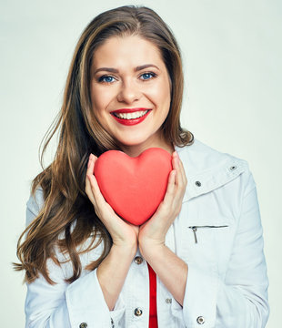 Isolated portrait of smiling young woman holding red heart.