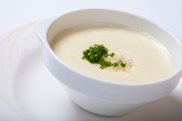 delicious creamy soup with parsley and cheese on white dish