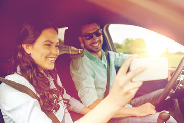 happy couple in car taking selfie with smartphone