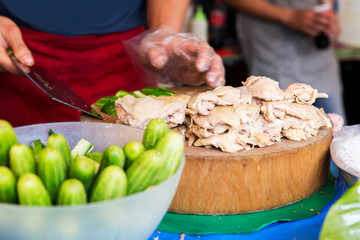 cook with poultry and cucumbers at street market