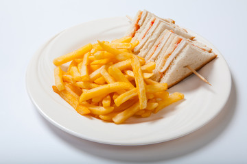 Club sandwiches with chicken and french fries on a white plate
