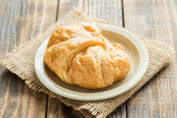 Croissant on a plate on old wooden table