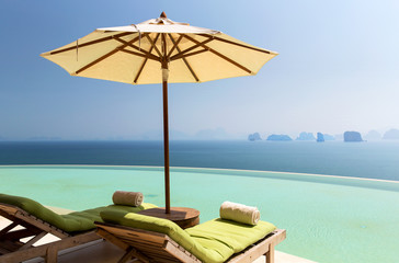 infinity pool with parasol and sun beds at ocean