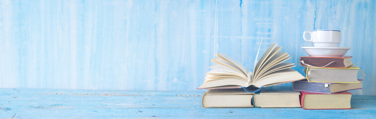 opened book, cup of coffee on blue grungy background, panoramic, copy space