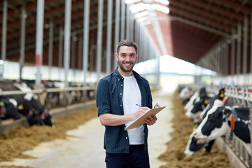 farmer with clipboard and cows in cowshed on farm