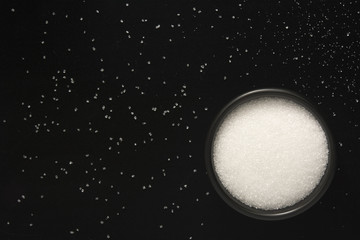 Naklejka premium Sugar in black bowl on black background