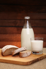 Milk and bread. Milk in a glass bottle and rye bread on a rustic wooden background. Bio products for the breakfast. Healthy food.
