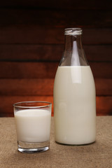 Milk in a drink glass and in a glass bottle on a rustic wooden background. Bio and organic products.