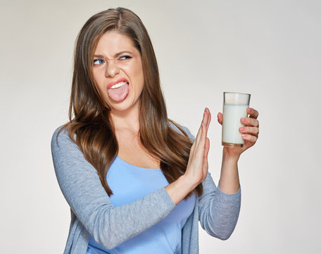 Young woman holding milk glass with disgust emotion.