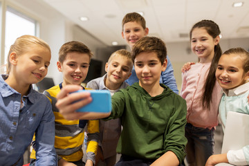 Obraz premium group of school kids taking selfie with smartphone