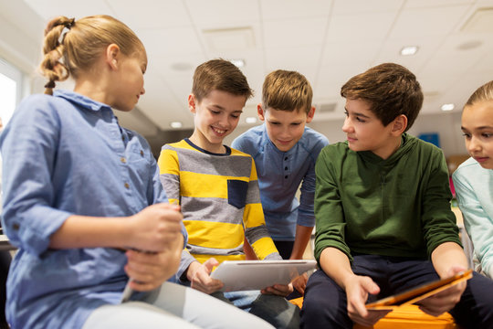 group of happy children with tablet pc at school