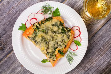 Baked salmon with spinach and cheese. Fish on white plate.