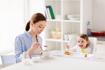 Obraz na płótnie Canvas happy mother and baby having breakfast at home