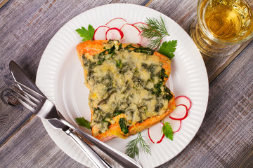 Baked salmon with spinach and cheese. Fish on white plate.