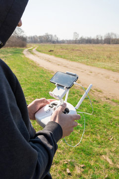 Demonstration of unmanned copter. Man controls quadrocopter flight. Flying the copter over a field. Remote control in a man's hands.