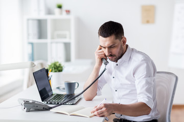 businessman with pad calling on phone at office