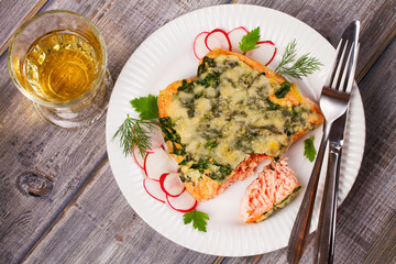Baked salmon with spinach and cheese. Fish on white plate.