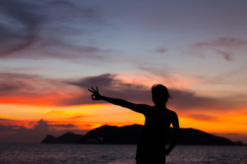 Silhouette of a woman  show Okay sign on sunset background