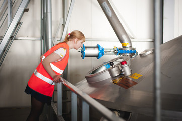 Female worker on beer factory. portrait woman in robe, standing on background line Food production,...