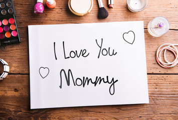 Mothers day composition. Note and beauty products on table.