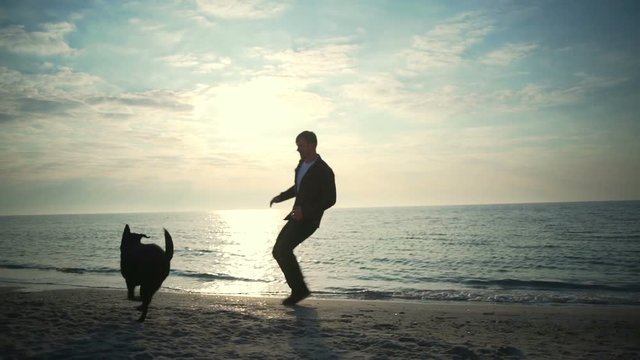 Young male run with his black dog at the sea slow motion
