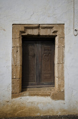 Fototapeta na wymiar Ein altes Fenster mit geschlossenen Holzläden in einem Fensterrahmen aus Natursteinen. 